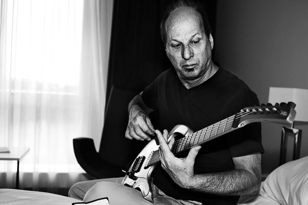 Guitaristen Adrian Belew siddeer på hotelværelset og skifter strenge inden koncerten i 2016