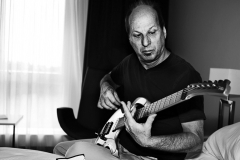Guitaristen Adrian Belew siddeer på hotelværelset og skifter strenge inden koncerten i 2016